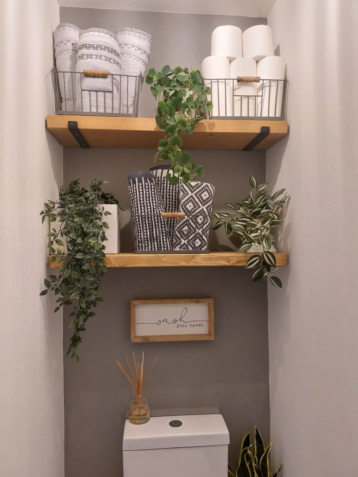 a bathroom with two shelves above the toilet and plants in baskets on top of them