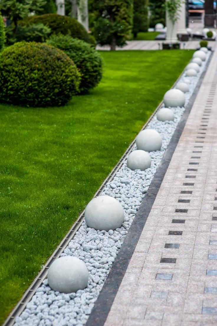 the walkway is lined with white balls and gravel, along with some green grass in the background