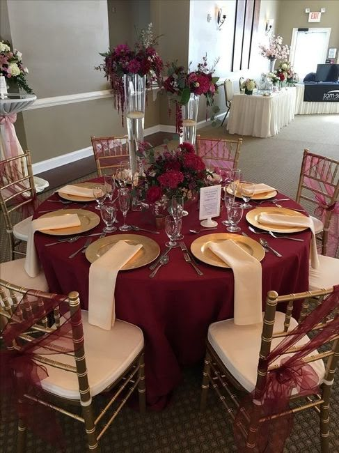 the table is set with red cloths and gold place settings, along with silverware