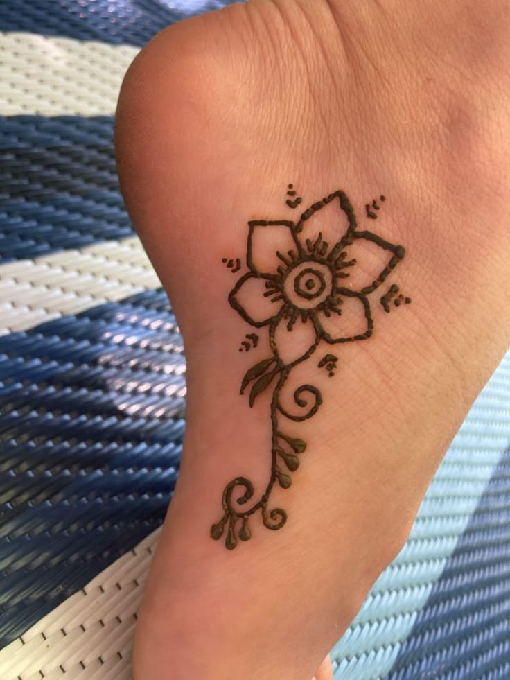 a small tattoo on the foot of a woman's foot with a flower design