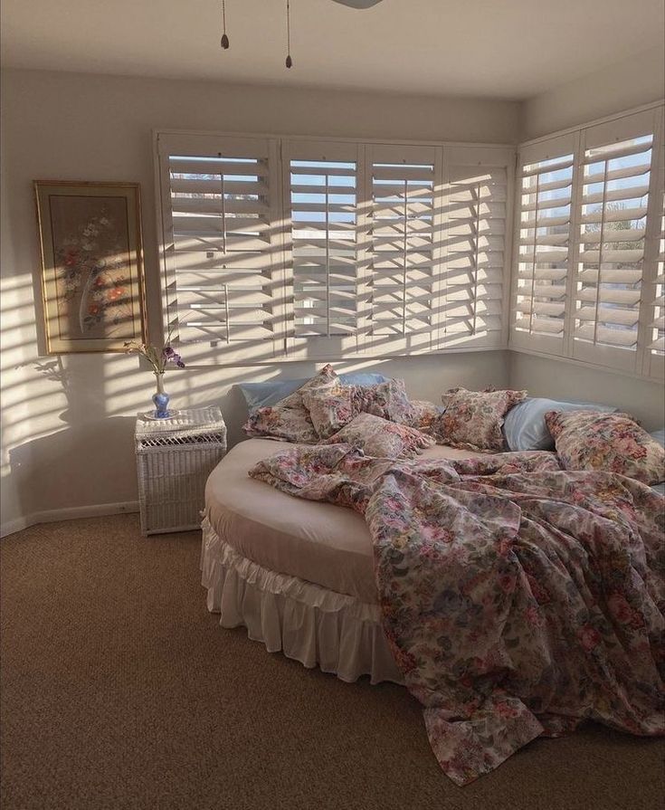 a bed sitting in a bedroom next to a window with blinds on top of it