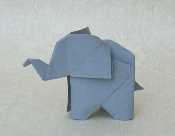 an origami elephant made out of blue paper on a white surface with no background