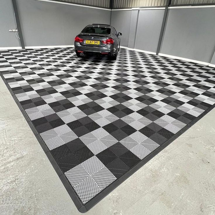 a black and white checkered floor with a car parked in the garage next to it