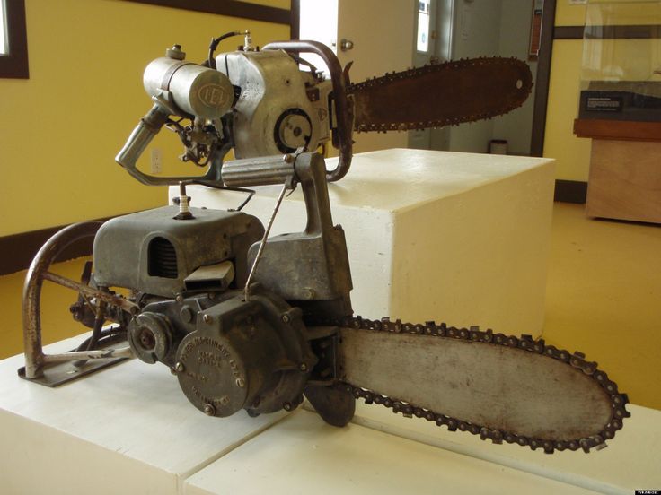 an old chainsaw sitting on top of a white table next to a yellow wall