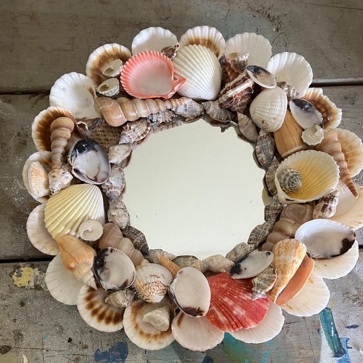 a wreath made out of seashells on top of a wooden table next to a mirror