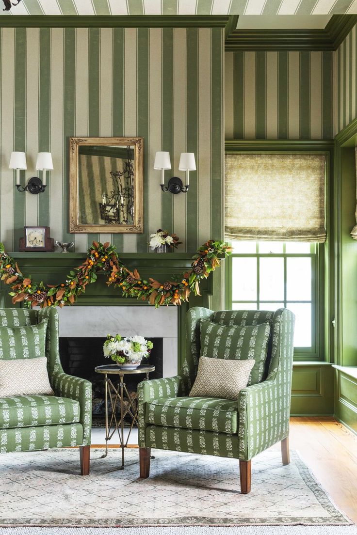 two green chairs in front of a fireplace with wreaths on the mantel above