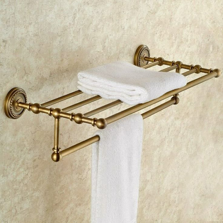 a towel rack with two towels hanging from it's sides and gold fixtures on the wall