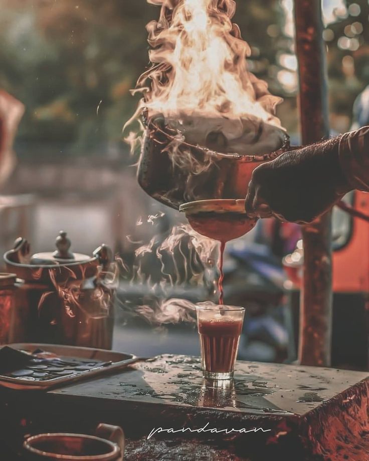 a person pouring something into a glass on top of a table