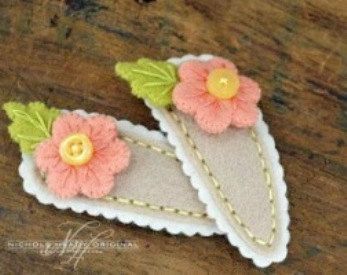 two felt flowers with green leaves on them