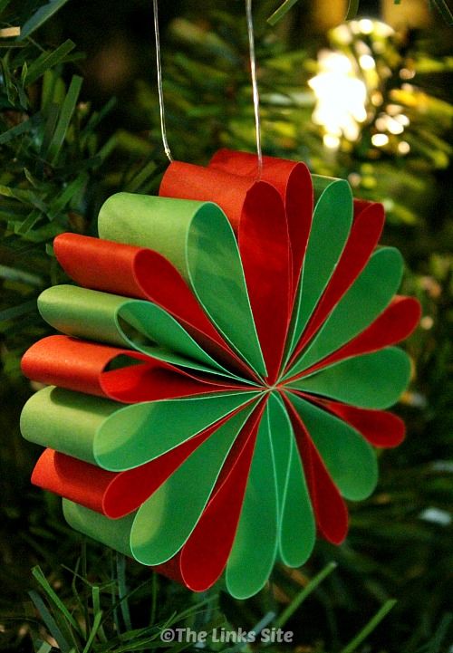 an ornament hanging from a christmas tree decorated with red, green and orange paper