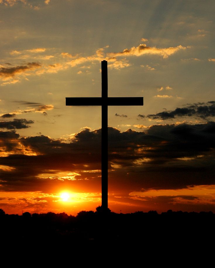 the sun is setting behind a large cross