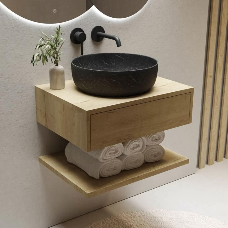 a black bowl sink sitting on top of a wooden shelf next to a mirror and towel rack