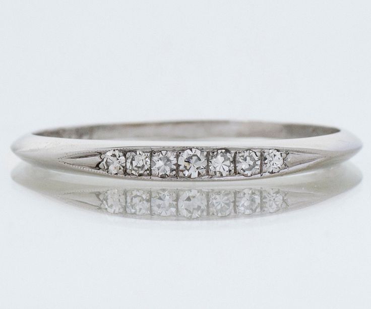 a white gold ring with five diamonds on the side and an old style wedding band