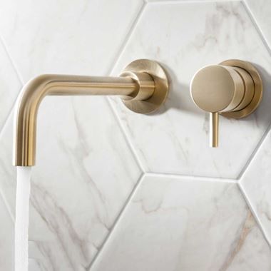 the brass faucet is attached to the white tile wall in this modern bathroom