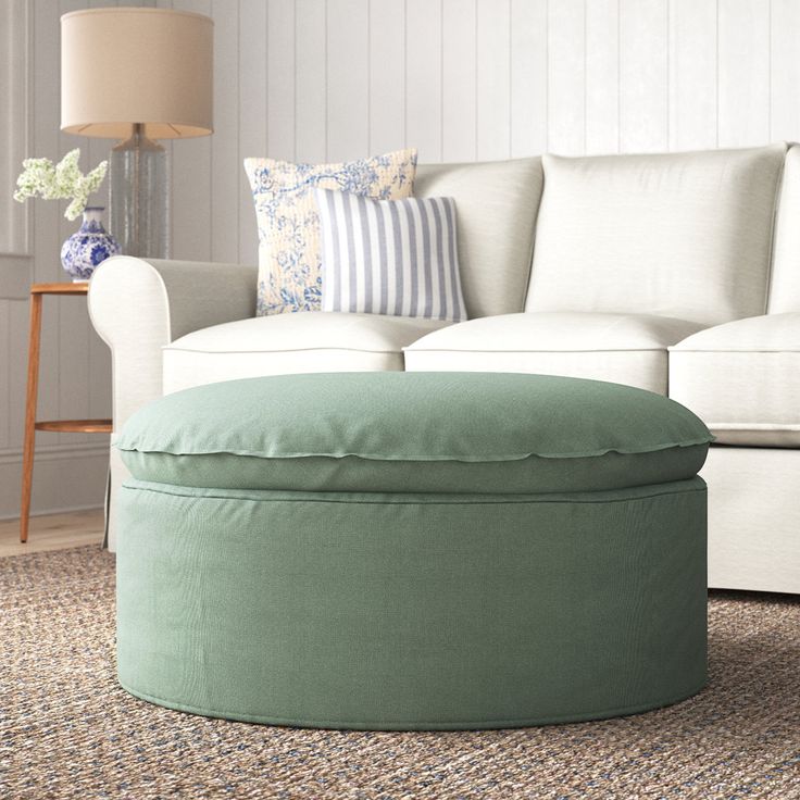 a living room with a white couch and green ottoman