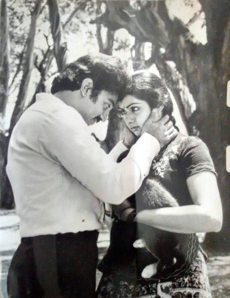 an old black and white photo of two people hugging each other with trees in the background