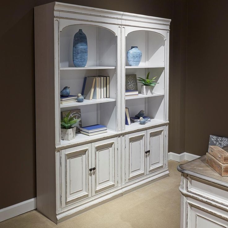 a white bookcase with blue vases and books on it in a living room