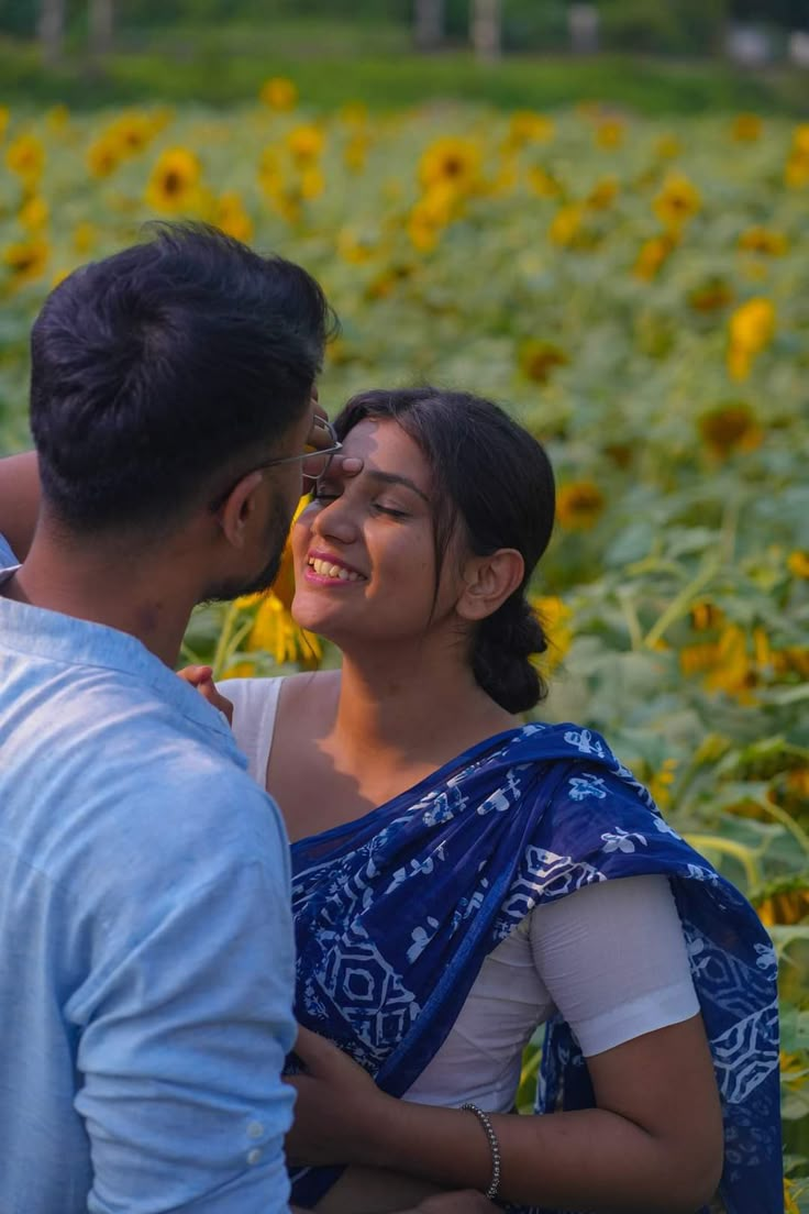 a man and woman standing next to each other in a field of sunflowers