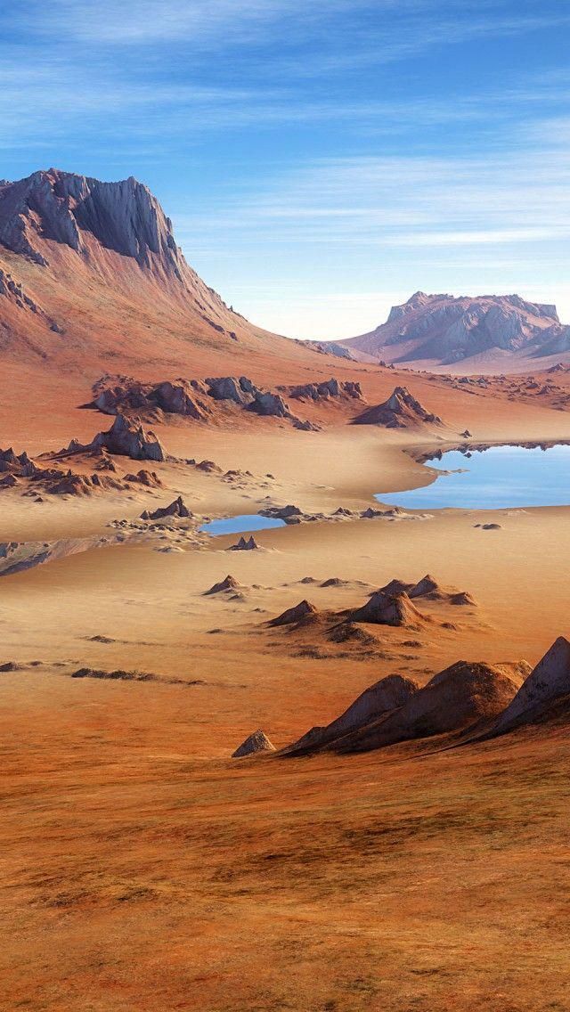 an arid landscape with water and mountains in the background