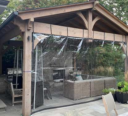 a covered patio with an outdoor fireplace and grill