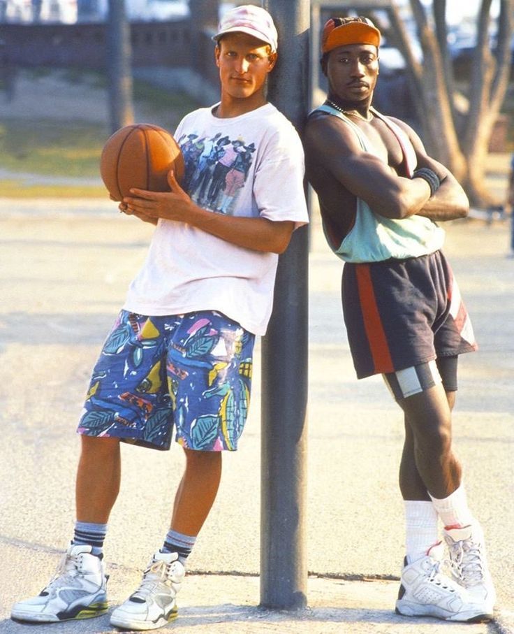 two men standing next to each other holding basketballs