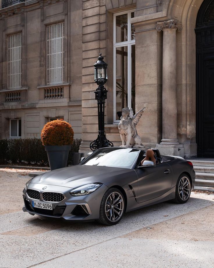 a silver convertible car parked in front of a large stone building with columns and windows