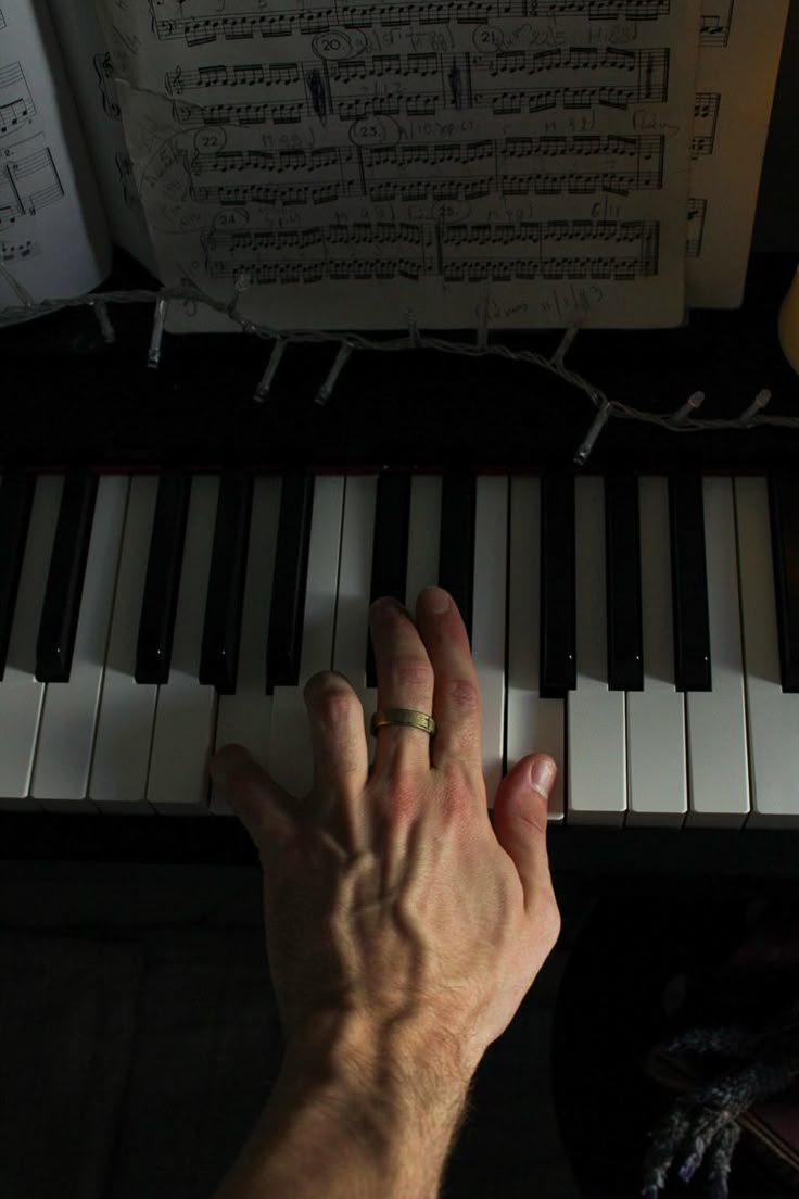 a person's hand resting on the keys of a piano