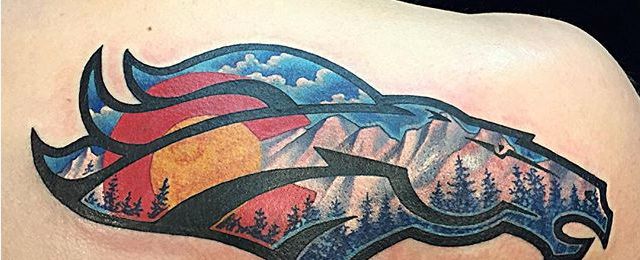 a tattoo on the back of a man's shoulder with mountains and trees in the background