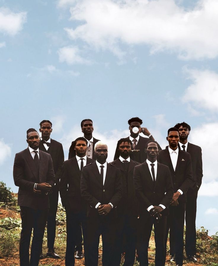 a group of men in suits standing next to each other on top of a hill