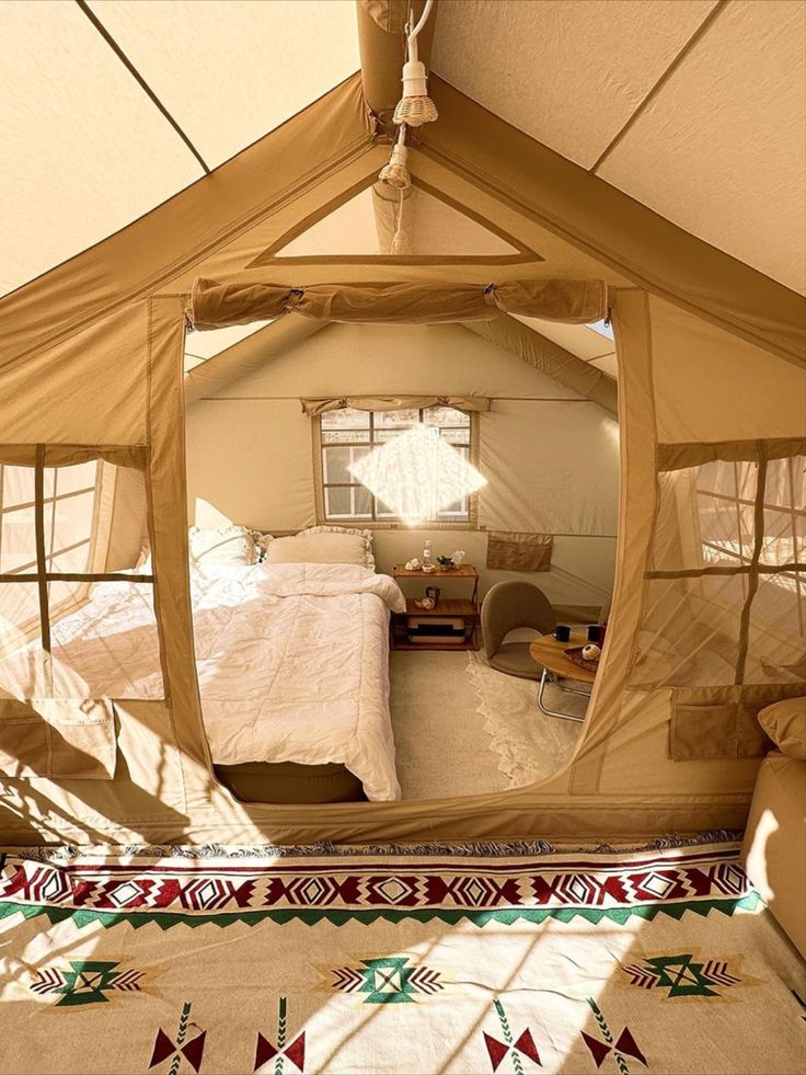 a bed sitting inside of a tent on top of a floor next to a window