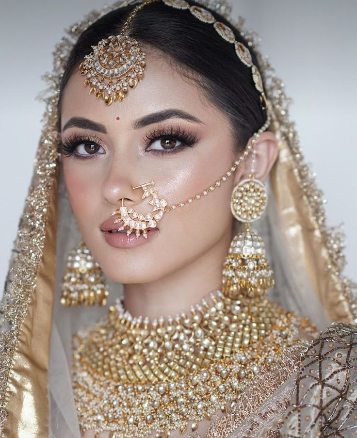 a woman wearing gold jewelry and veil with her nose ring in front of her face