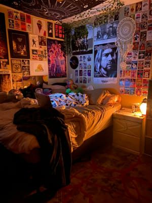 a bed room with a neatly made bed and lots of posters on the wall above it