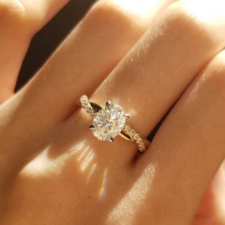 a woman's hand with a diamond ring on top of her finger and the other hand holding an engagement ring