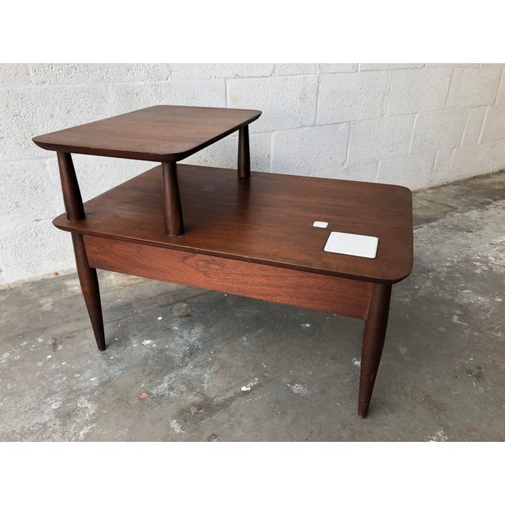 two tables sitting on top of each other in front of a white brick wall and cement floor