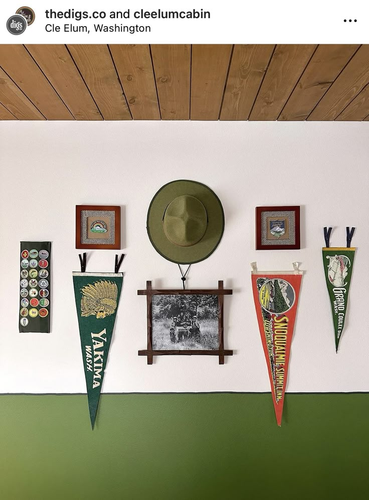 there are many pennants hanging on the wall with hats and pictures hung above them