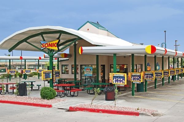 a fast food restaurant with tables and chairs in the parking lot next to each other