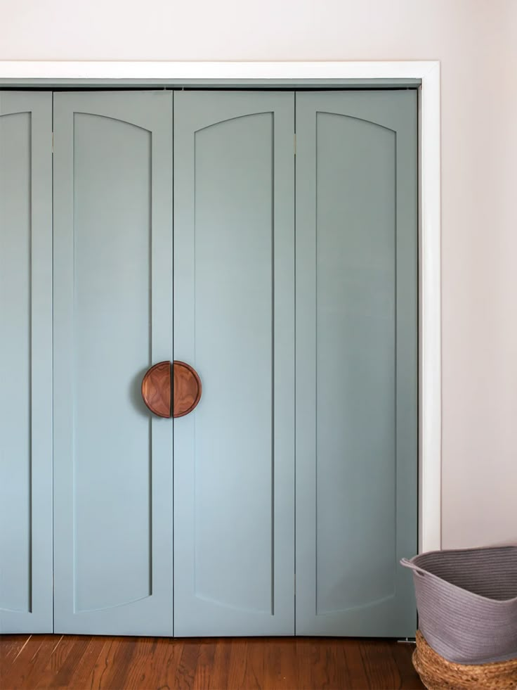 a blue door with a round wooden knob on it's side in front of a white wall