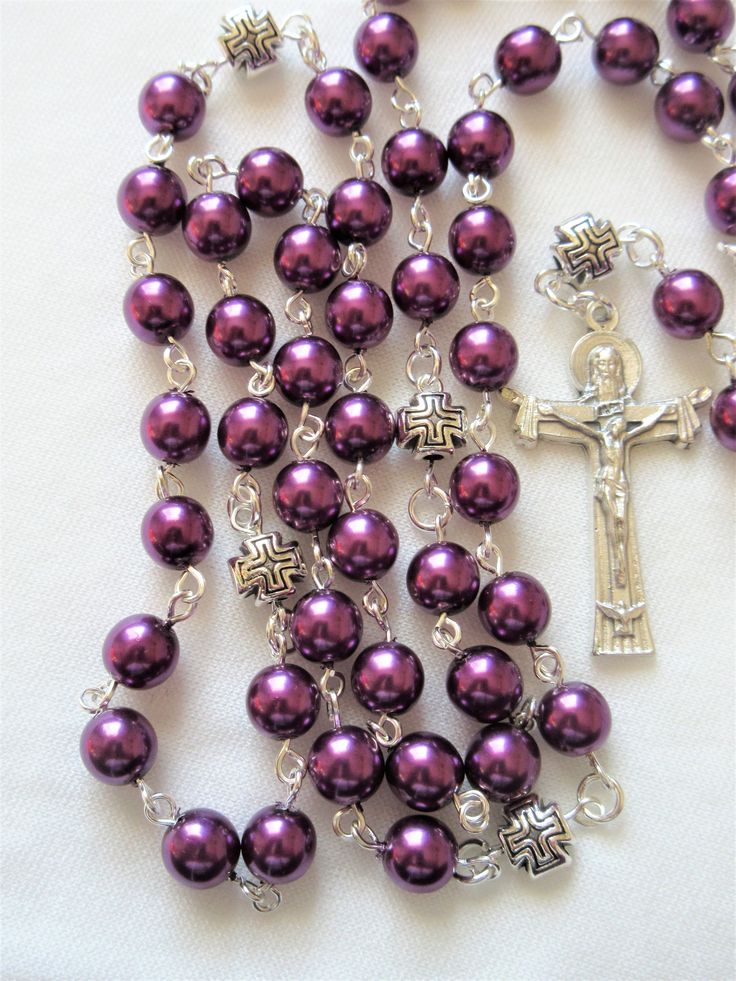 This plum purple Catholic rosary is made with larger 8mm Czech glass pearls. It has a Holy Trinity crucifix and a Miraculous medal connector. The Pater beads are 8mm puffed pewter cross beads. All of the silver plated wires are hand turned. The body of the rosary is 30 inches around and has a 5.5 inch cross drop. This rosary will be slipped into a velvet bag and shipped in a bubble mailer. Purple Rosary With 8mm Round Beads, Purple Rosary With 8mm Beads, Cross Beads, Catholic Rosary, Rosary Catholic, The Rosary, Miraculous Medal, Bubble Mailer, Holy Trinity