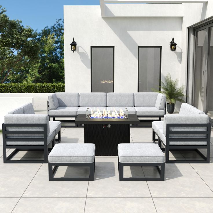 an outdoor living room with grey couches and fire pit