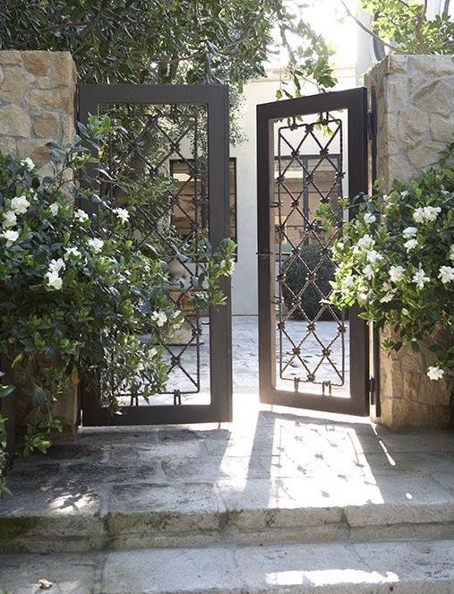 an open door leading into a garden with white flowers and greenery on either side