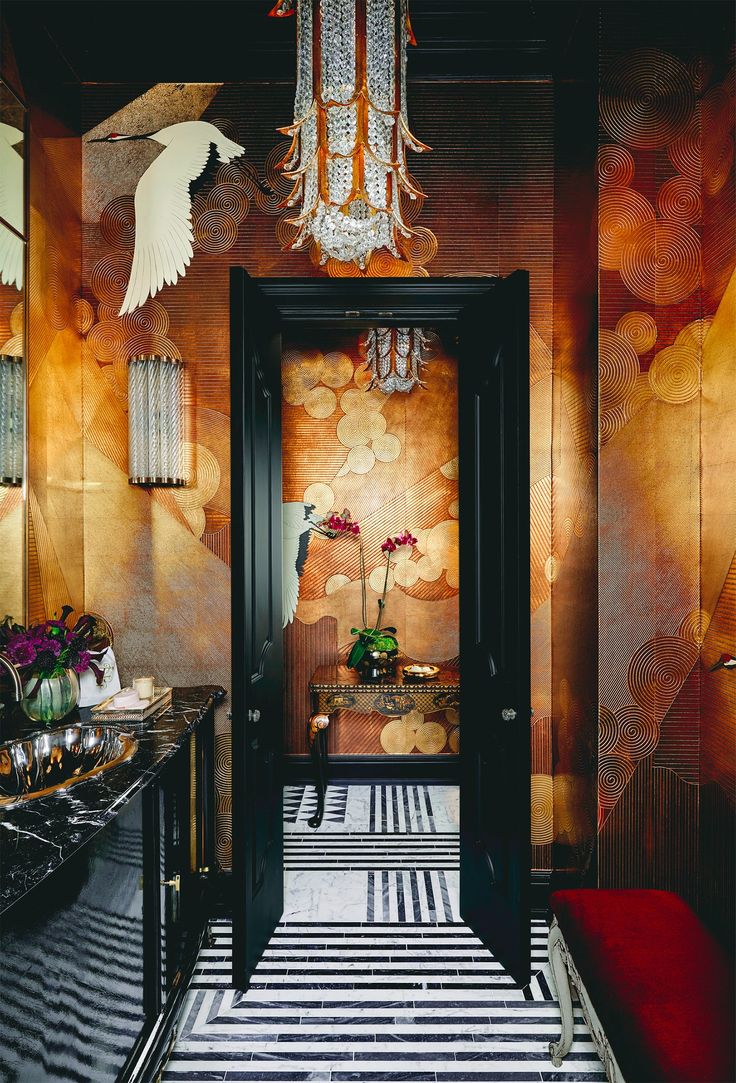 a hallway decorated in gold and black with an art deco chandelier hanging from the ceiling