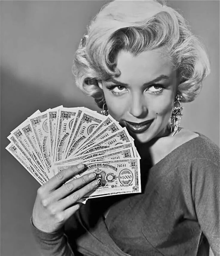 marilyn monroe holding money in one hand and looking at the camera with an expression on her face