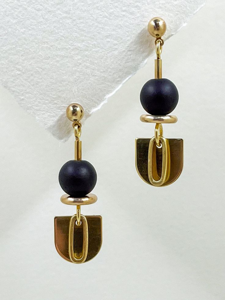 These earrings are sleek and modern, crafted from golden brass and semi precious stone.  The matte, black onyx stone features among the geometric shapes, an elongated semi-circle, layered with a solid brass oval hangs below, adding a touch of contrast and sophistication to the overall design.  The combination of geometric shapes, the matte black stone, and the metallic shine creates an elegant, minimalist aesthetic. A brass ball stud with stainless steel post holds the design from the top.  Approximate measurements- 4.5cms long 1.5cms wide All Set Theory jewellery comes with care instructions and a polishing pad to keep your jewellery looking shiny and fabulous! ✨ Black Brass Earrings, Modern Gold Onyx Earrings, Black Minimalist Metal Earrings, Modern Black Geometric Earrings, Minimalist Black Linear Drop Earrings, Modernist Black Earrings For Gift, Modernist Black Earrings As Gift, Modern Onyx Drop Earrings, Minimalist Black Drop Earrings