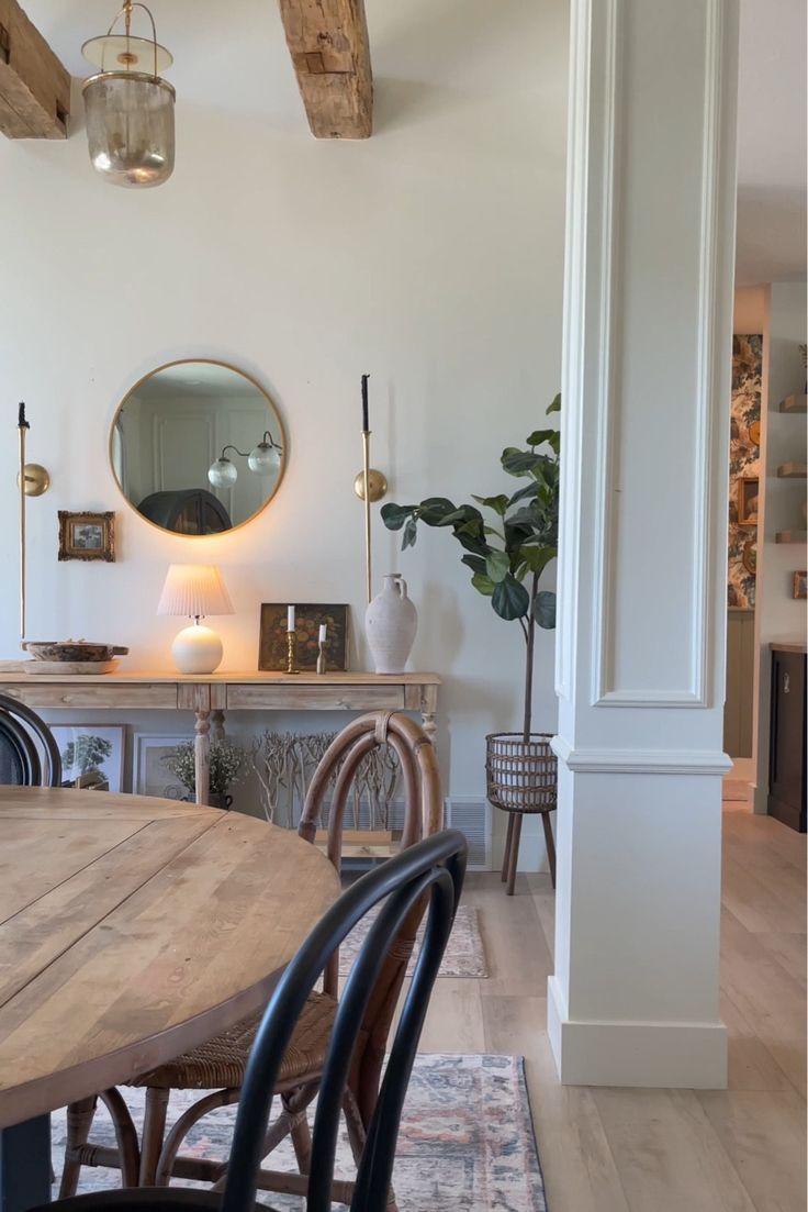 a dining room table and chairs in front of a mirror on the wall above it