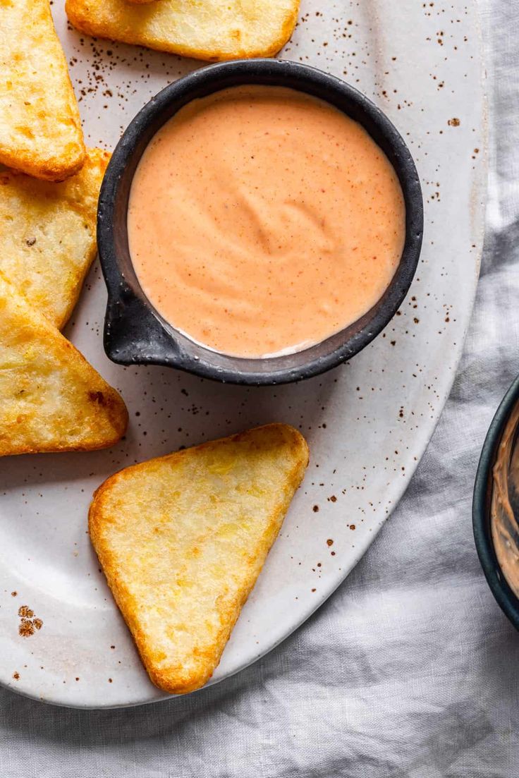 grilled cheese wedges with dipping sauce on a plate next to a bowl of dip