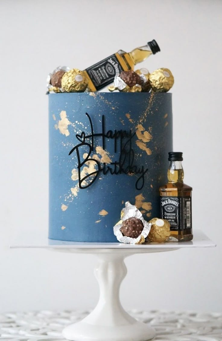 a blue birthday cake with gold sprinkles and chocolate candies on top