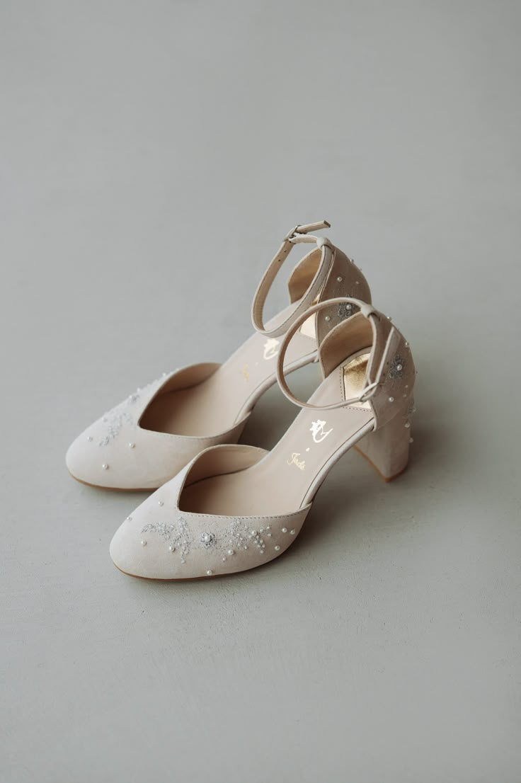 a pair of white high heeled shoes sitting on top of a gray floor next to each other