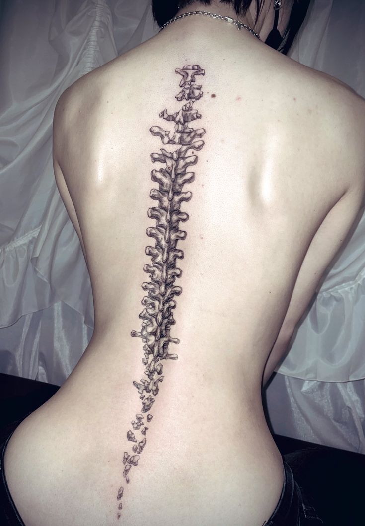 the back of a woman's body with a tattoo design on her lower back