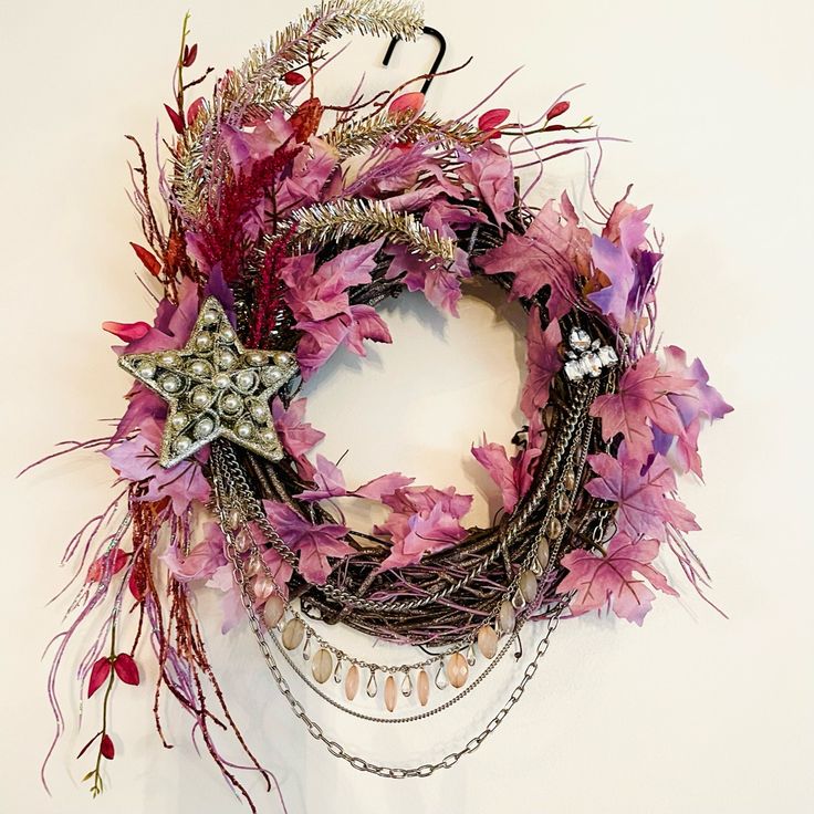 a wreath with purple flowers and chains hanging from it's side on a white wall