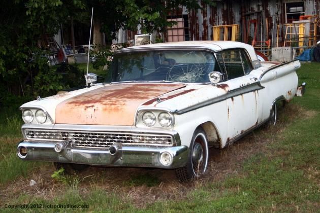 an old rusty car parked in the grass